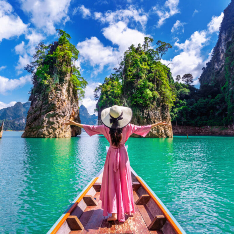 Beautiful girl standing on the boat and looking to mountains in